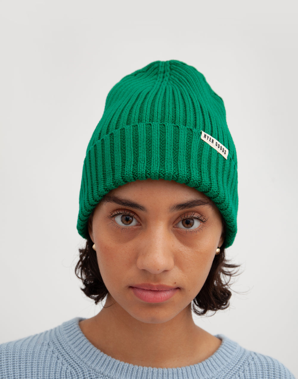 a headshot of a girl wearing a light blue sweater and a green beanie