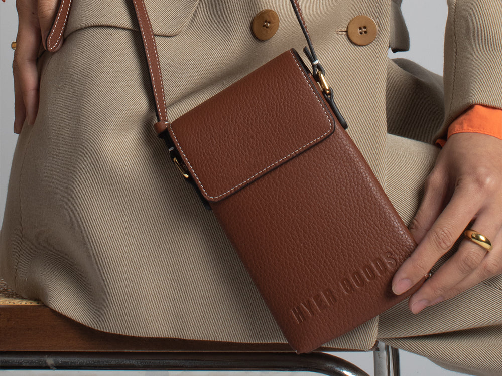 a close up shot of a tan phone sling with white stitching
