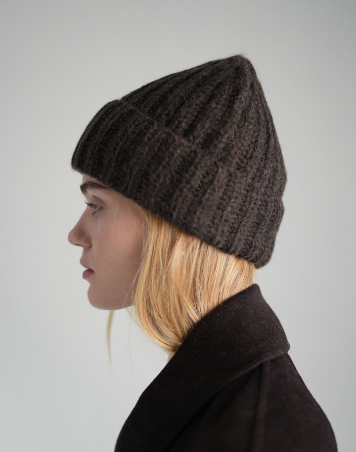 a profile of a women wearing a brown chunky ribbed beanie and a brown wool coat #color_brown