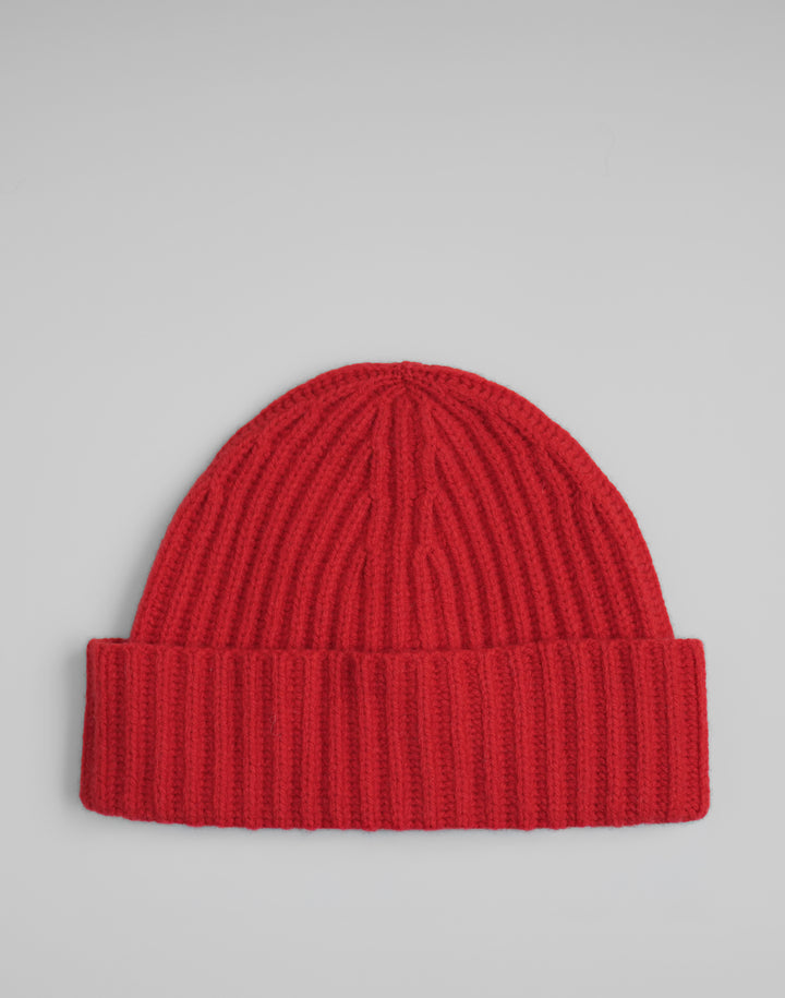 A bright red ribbed knit beanie hat with a folded cuff, photographed flat against a light gray background. #color_red