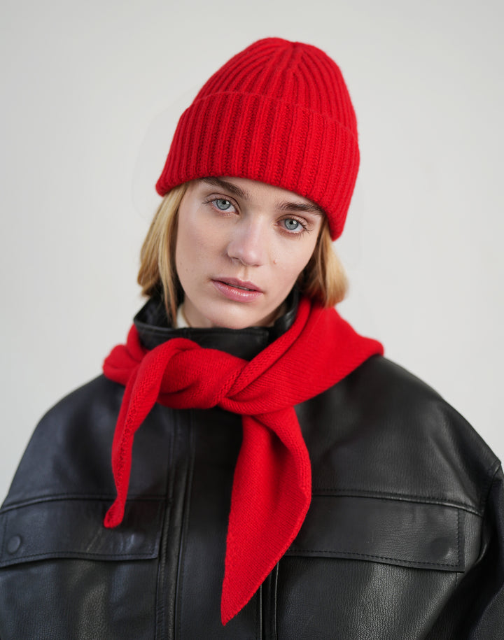 a woman wears a black leather jacket and a matching red ribbed beanie and a bandana scarf tied around her neck #color_red