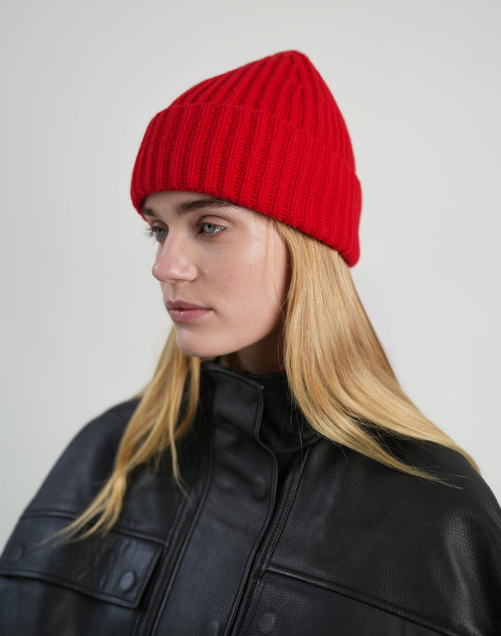 a woman in a black leather jacket and a red ribbed wool beanie #color_red