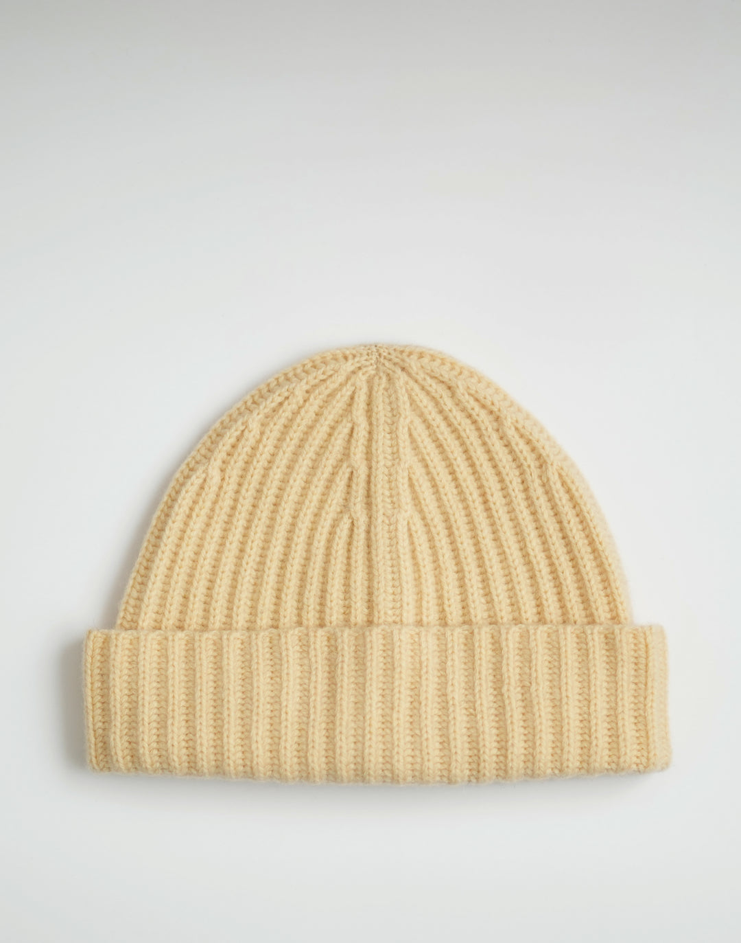 A light beige ribbed knit beanie hat, shown flat against a light gray background. #color_butter-yellow