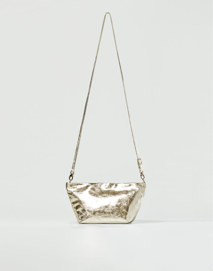 a gold leather crossbody bag with long this strap on a light grey background #color_gold