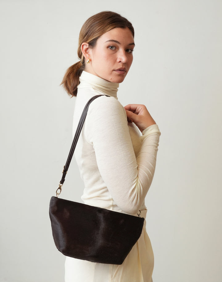 a woman in a cream turtleneck wears a HYER GOODS La Sala mini convertible shoulder bag in dark chocolate pony hair #color_dark-chocolate-pony