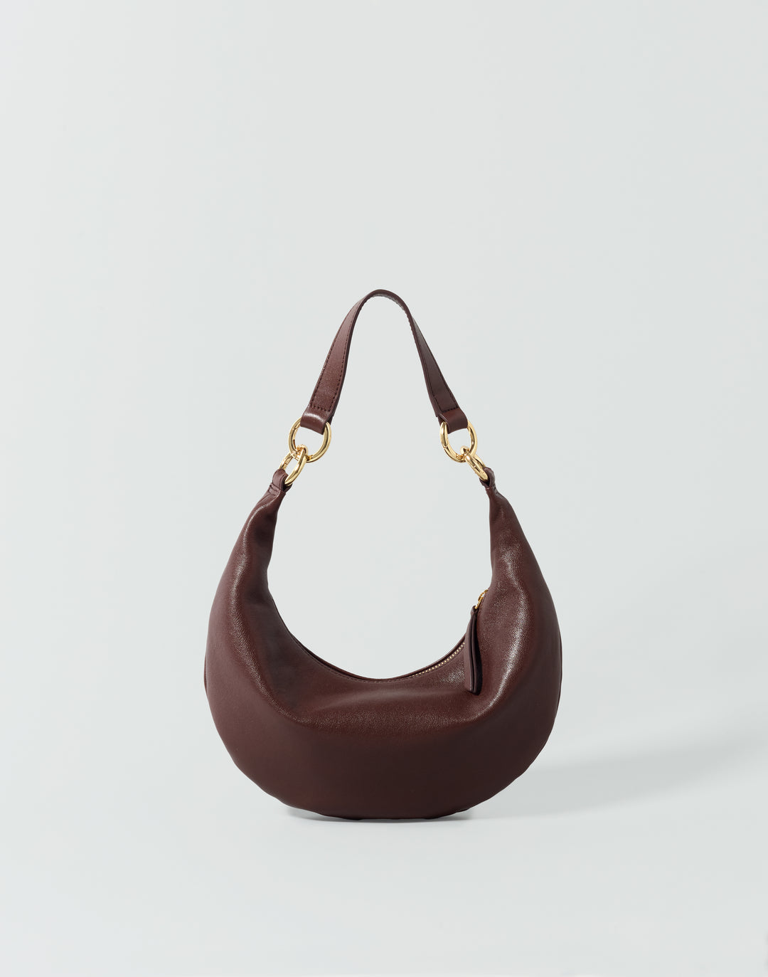 A reddish brown leather crescent-shaped shoulder bag with gold-tone hardware, displayed on a light gray background. #color_bordeaux-vintage