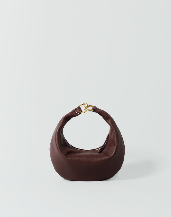 A reddish brown HYER GOODS micro ring bag crescent-shaped mini shoulder bag with a gold-tone metal clasp, set against a plain light gray background. #color_bordeaux-vintage