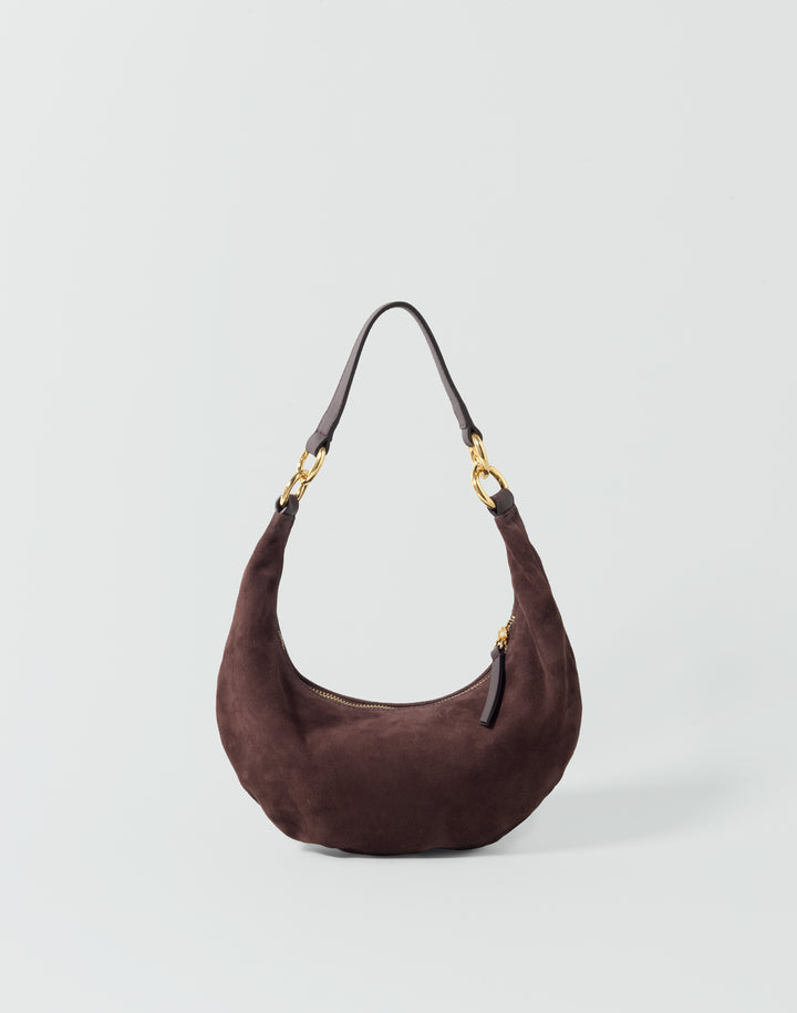 a dark brown suede crescent-shaped shoulder bag with gold-tones hardware against a grey background #color_chocolate-suede