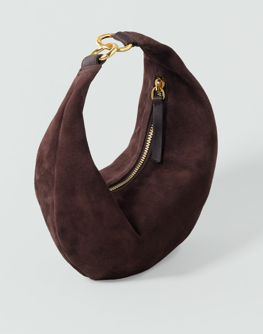 A dark brown suede crescent shoulder bag with gold-tone hardware and a black zipper pull, shown on a light gray background.#color_chocolate-suede