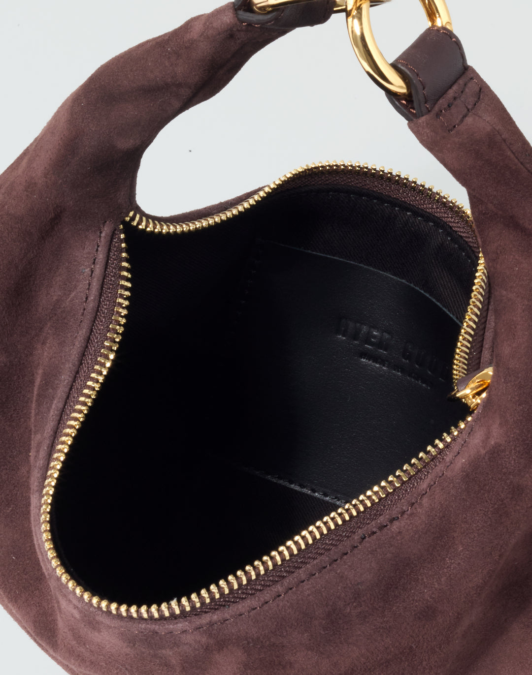 Close-up of a dark brown suede shoulder bag showing the interior with a black lining, gold zipper, and a gold metal ring attachment. #color_chocolate-suede