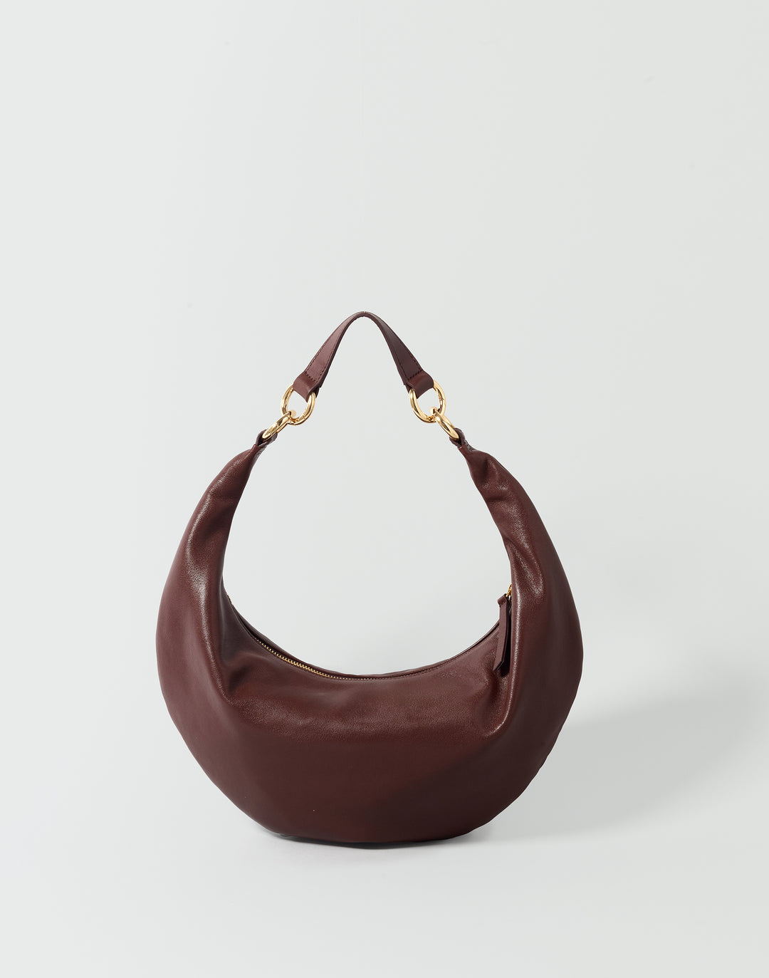 A crescent-shaped leather shoulder bag in a deep burgundy brown, featuring gold-tone hardware and a single strap, photographed on a light gray background.#color_bordeaux-vintage