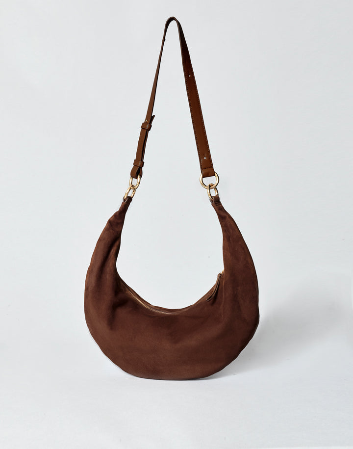 hyer goods ring bag convertible leather crescent bag in a dark brown suede with adjustable long leather strap and gold hardware against a grey background #color_chocolate-suede