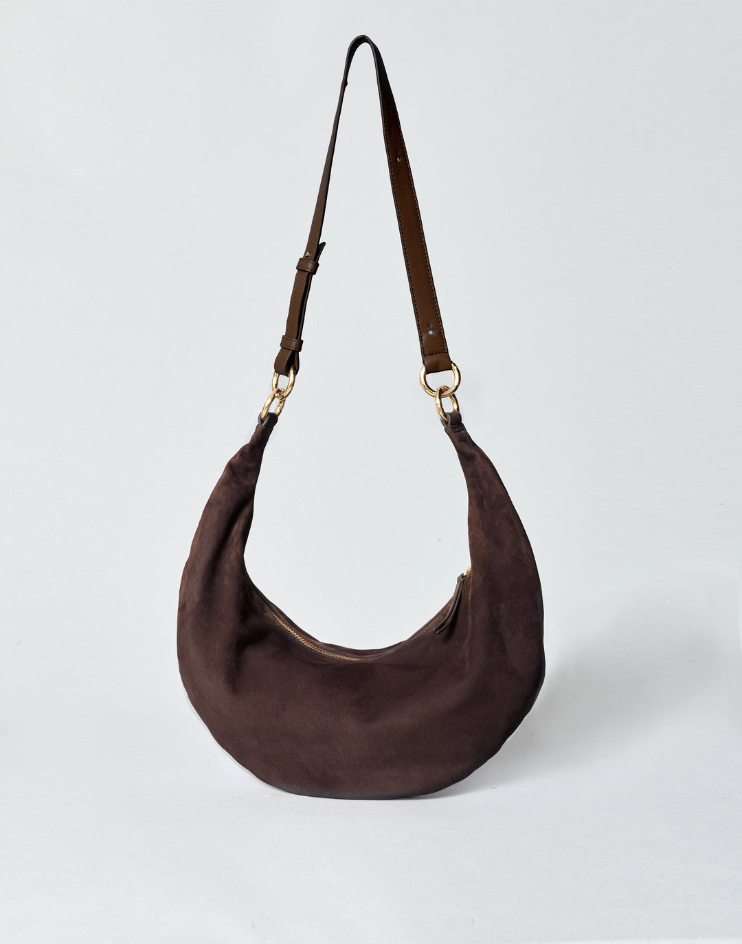 hyer goods ring bag convertible leather crescent bag in a dark brown suede with adjustable long leather strap and gold hardware against a grey background #color_chocolate-suede