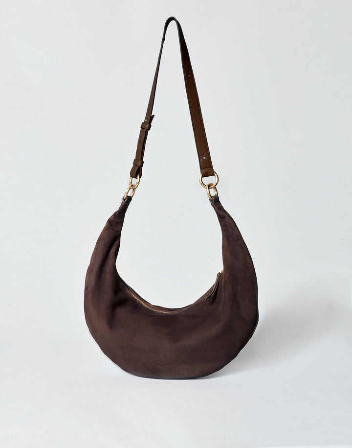 hyer goods ring bag convertible leather crescent bag in a dark brown suede with adjustable long leather strap and gold hardware against a grey background #color_chocolate-suede