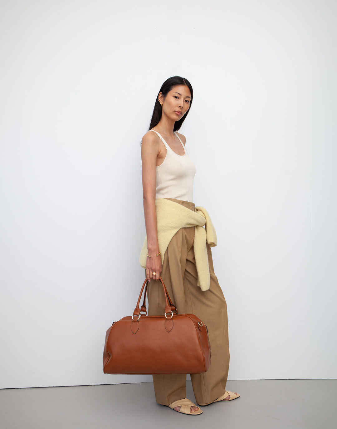 HYER GOODS tan leather la via weekender duffel bag held by model #color_cognac