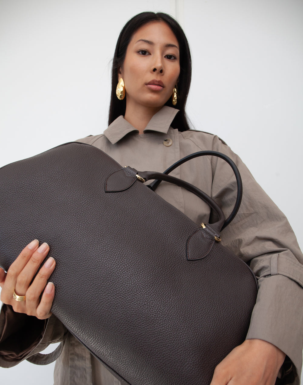 close up of HYER GOODS dark brown leather la via weekender duffel bag held by model #color_dark-chocolate