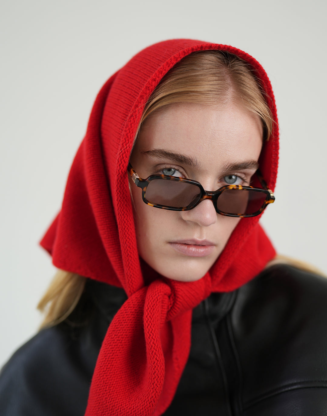 a close up shot of a woman wearing a black leather jacket and red bandana scarf around her head #color_red