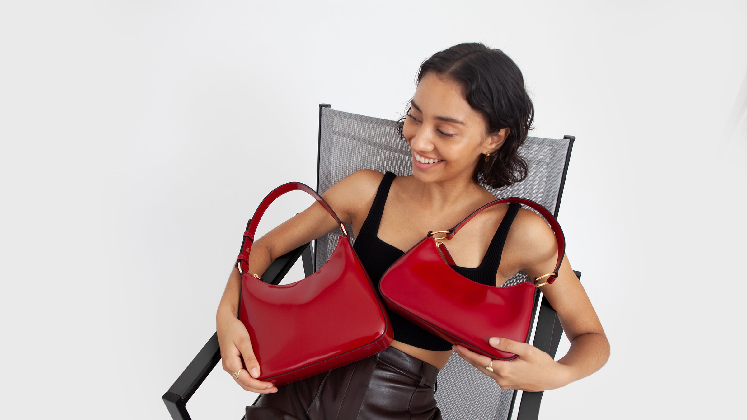 a girl sits in a chair holding two red shoulder bags in her lap